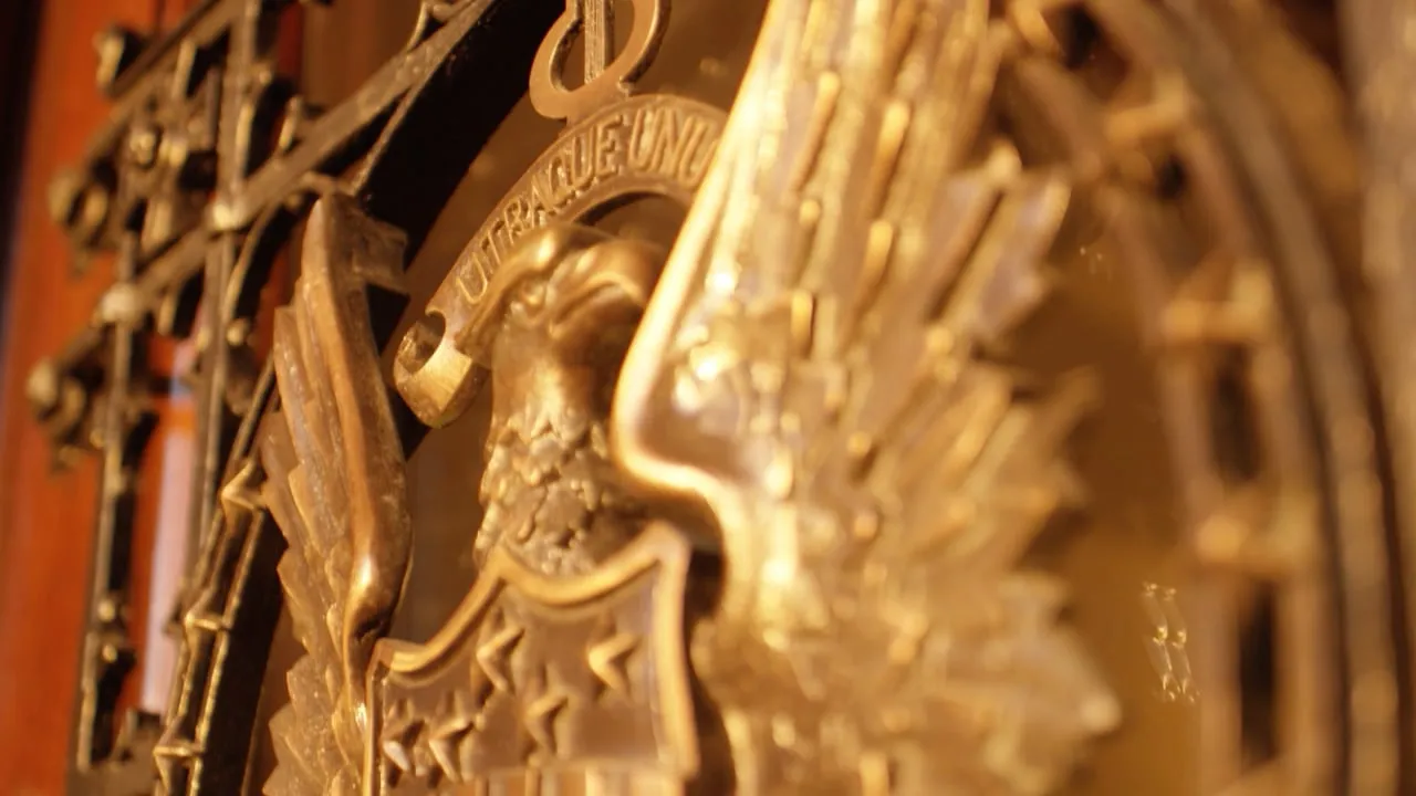 Detail of an ornate gilded sculpture lit in warm amber light.