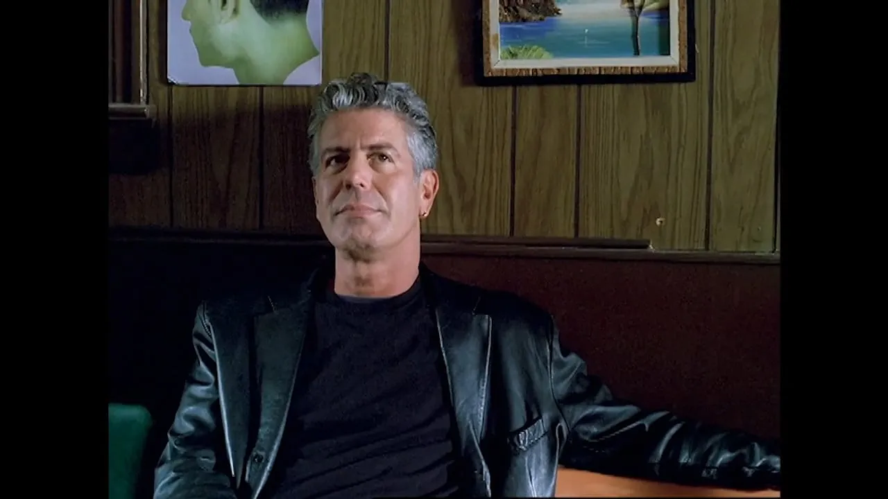 Anthony Bourdain seated in a dimly lit wood-panelled bar.