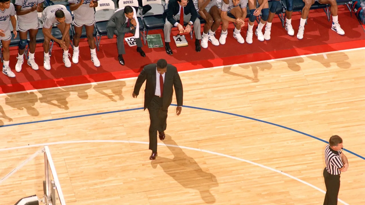 A basketball coach walking the court during a game.